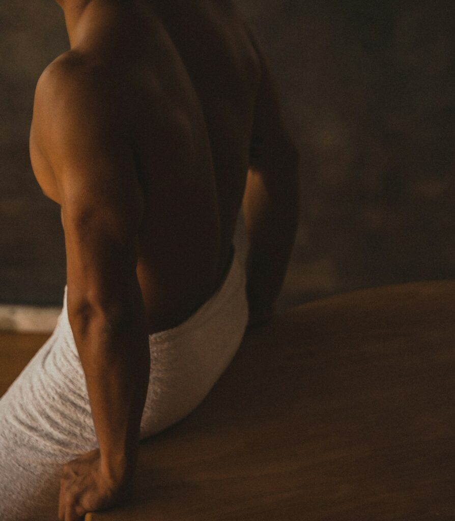 Mann, der mit einem Saunhandtuch bekleidet auf einer Saunabank entspannt.